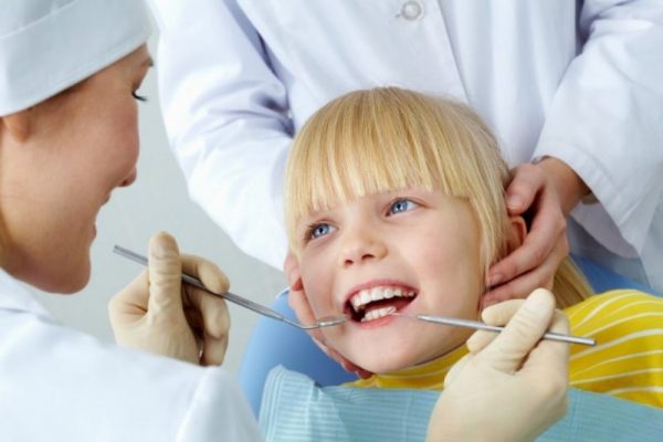 A child getting his teeth checked by an dentist.