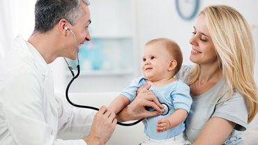 A doctor is examining a baby with a stethoscope.
