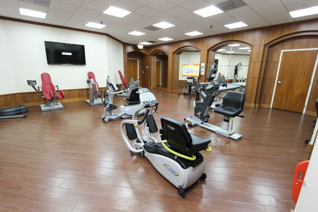 A gym with many different machines and wooden floors